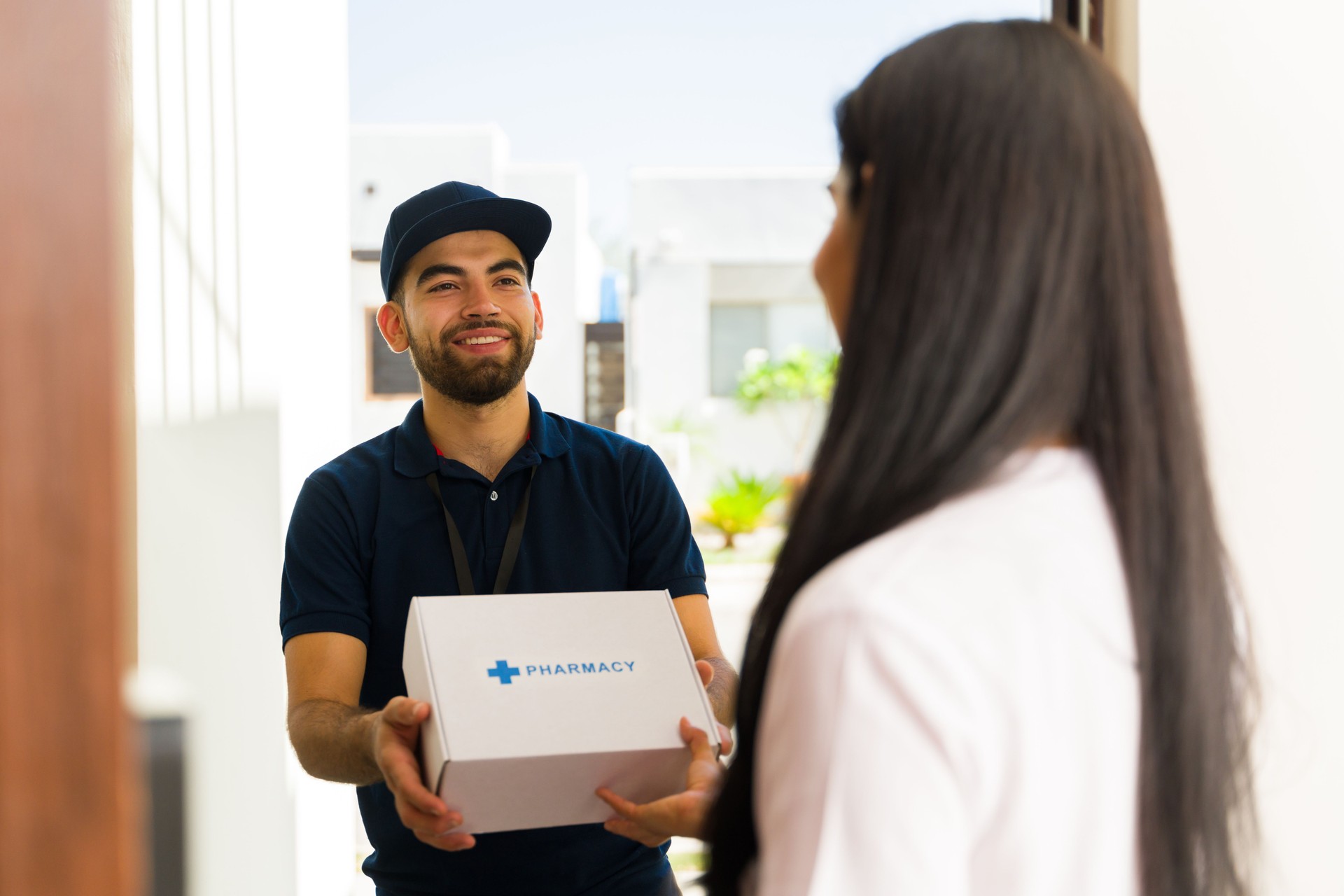 Cheerful delivery man is delivering a package of prescription medication to a woman at her doorstep